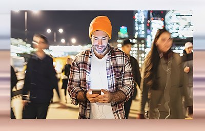 Foto einer Personengruppe mit einem Mann im Vordergrund, der ein Smartphone hält 